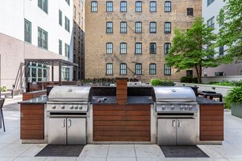 the outdoor kitchen has stainless steel appliances and a grill and a bar with a wood  at The Cosmopolitan, St Paul, MN, 55101